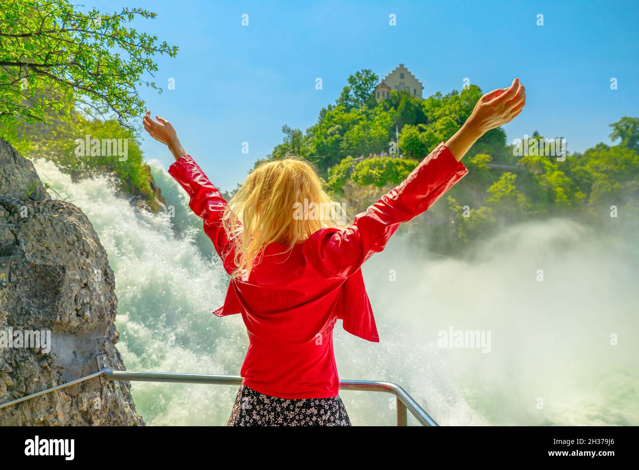 Donna che scherza la cascata svizzera Rheinfall in Svizzera. La cascata più potente e grande d'Europa, situata nei cantoni di Sciaffusa Foto Stock