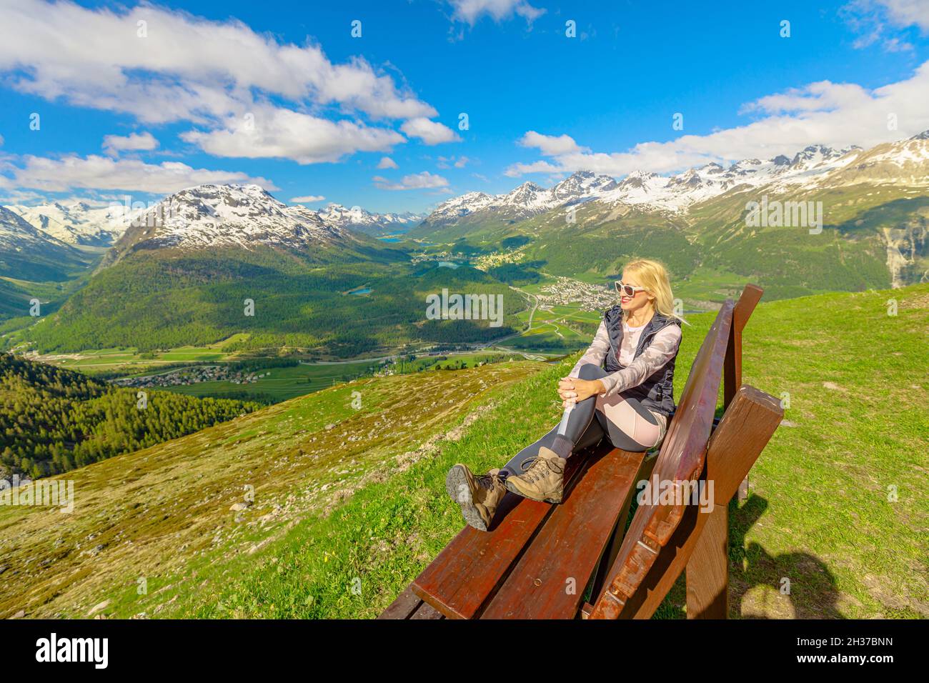 Donna che si rilassa su una panchina in cima alla stazione Muottas Muragl della famosa funicolare in Svizzera. Luogo popolare per escursioni in montagna in Foto Stock