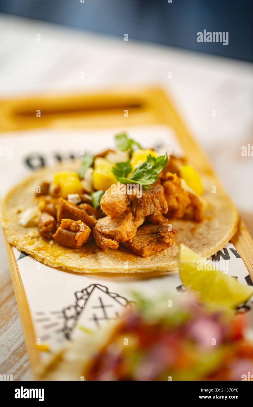 Il Taco è un piatto messicano tradizionale costituito da una piccola tortilla di granoturco o di granoturco ricoperta con un ripieno come carne, salsa di guacamole, vegetab Foto Stock