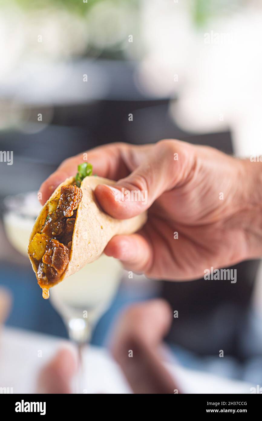 Salsa che sgocciola dal cibo messicano taco. Piatto costituito da un piccolo mais o tortilla di grano flapjack con un ripieno come la carne, guacamole sa Foto Stock