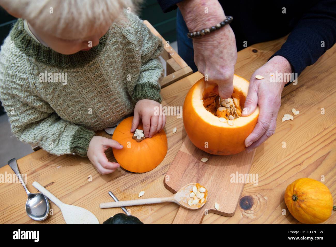 Un toddler e una nonna carve insieme una decorazione della zucca di halloween Foto Stock