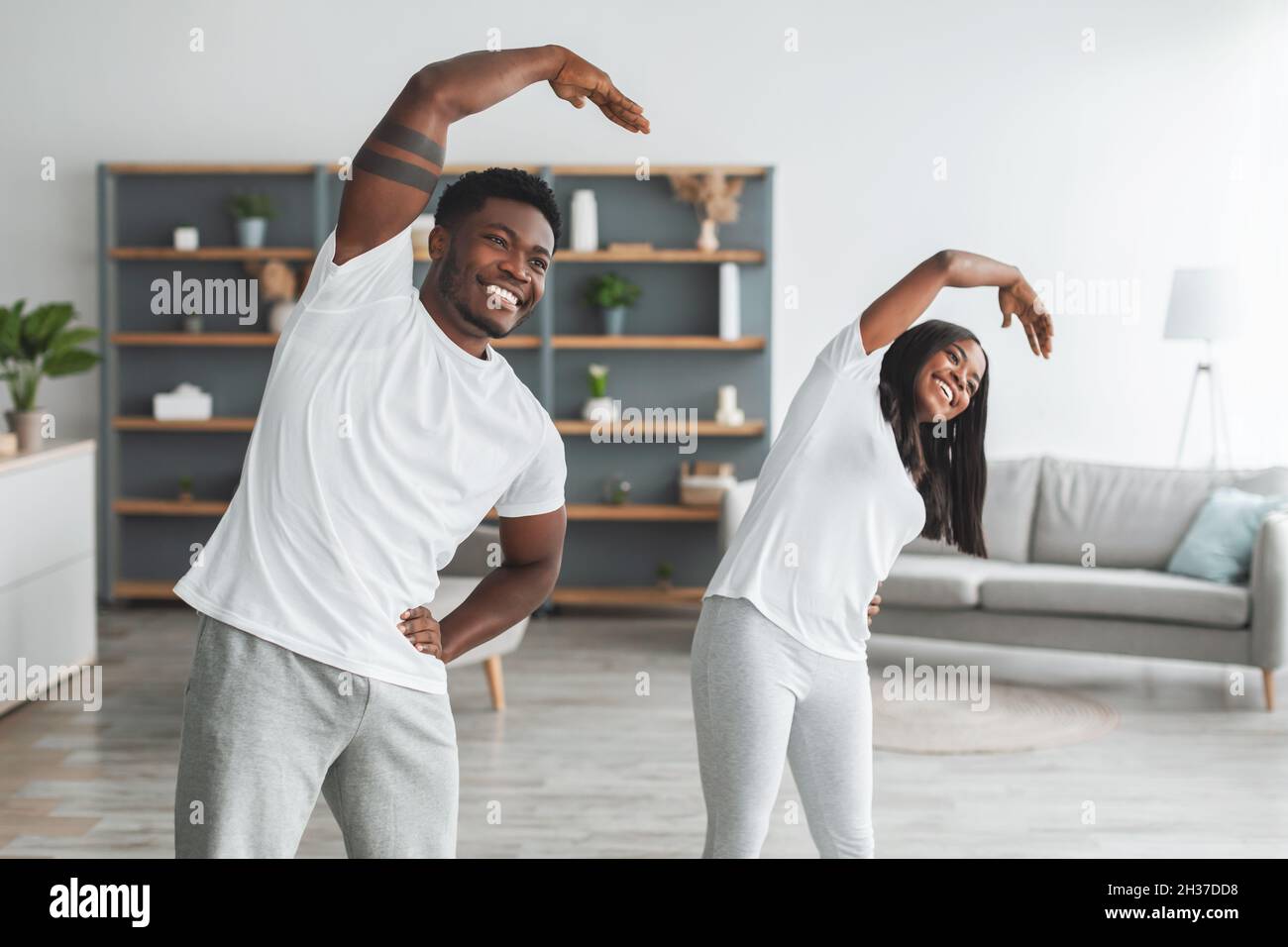 Giovane coppia nera che fa l'esercitazione di allungamento del braccio insieme Foto Stock