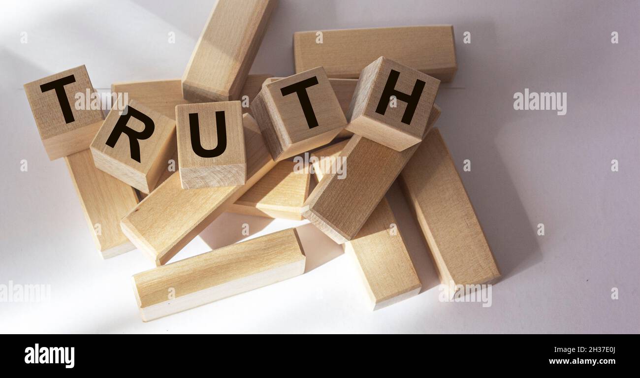 Verità - parola da blocchi di legno con lettere, fatti reali concetto di verità, lettere casuali intorno, sfondo bianco Foto Stock