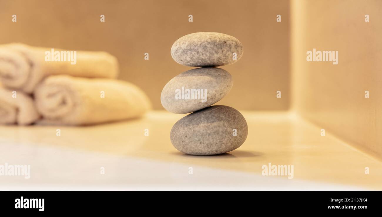 Pietre Zen, pebble lisce piramide impilato equilibrio, spa sfondo interno. Terapia naturale olistica e concetto di benessere Foto Stock
