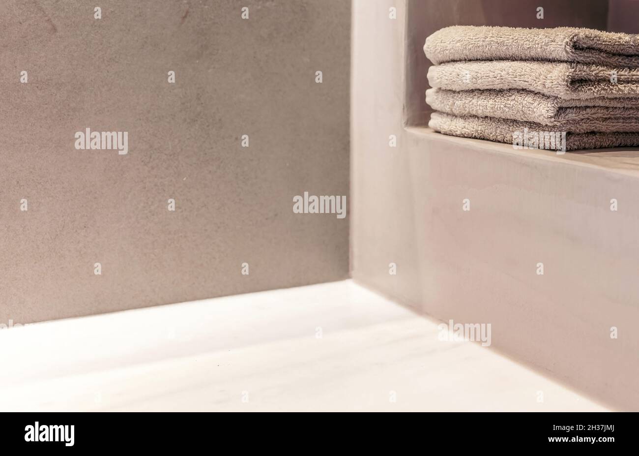 Bagno dal design moderno. Asciugamani puliti piegati impilati su uno scaffale primo piano vista, spazio copia, spa benessere camera modello Foto Stock