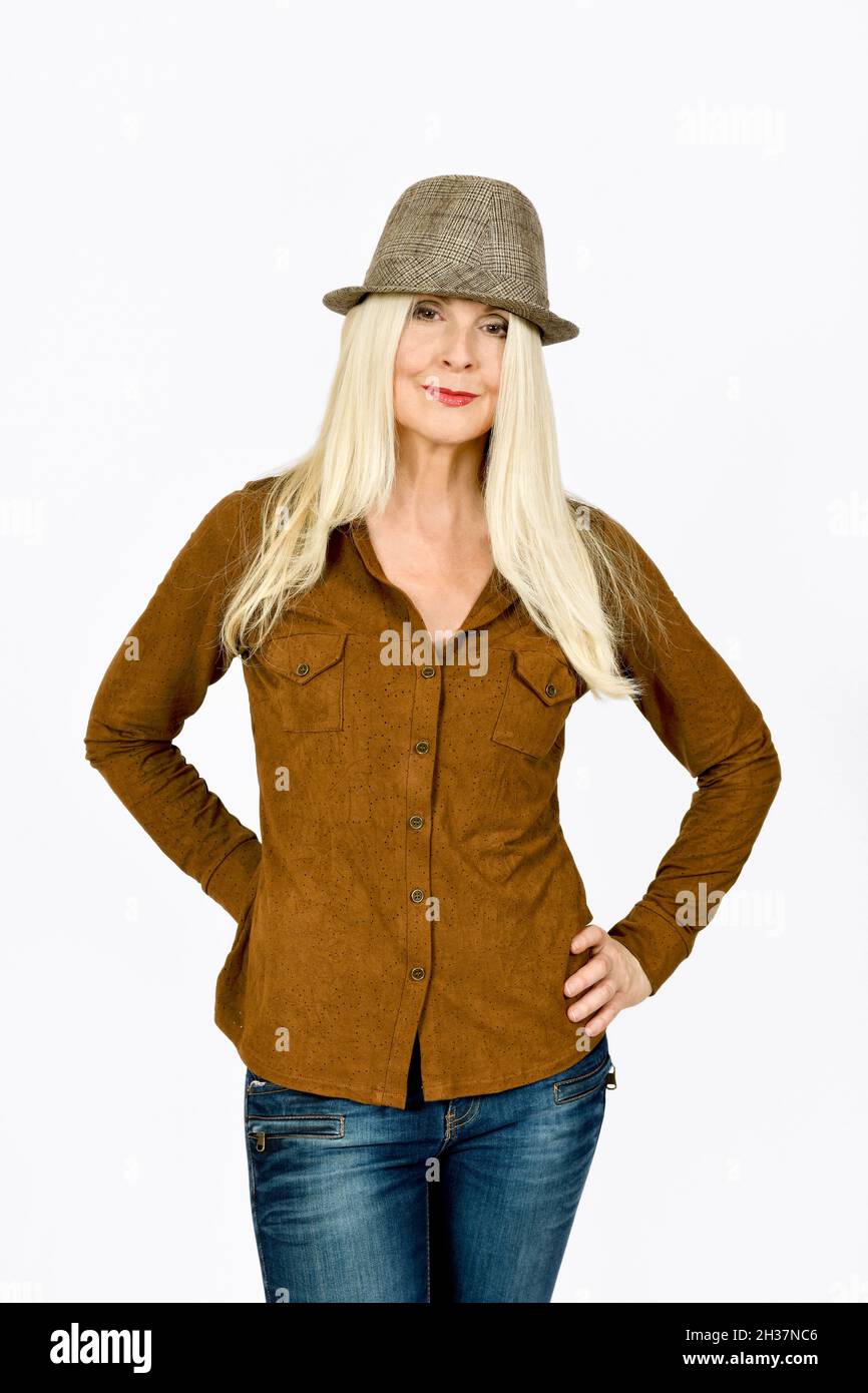 Bella Bionda Lady ripresa su sfondo bianco semplice con mani sui fianchi, indossare e cappello, e con un mezzo sorriso o sorriso Foto Stock