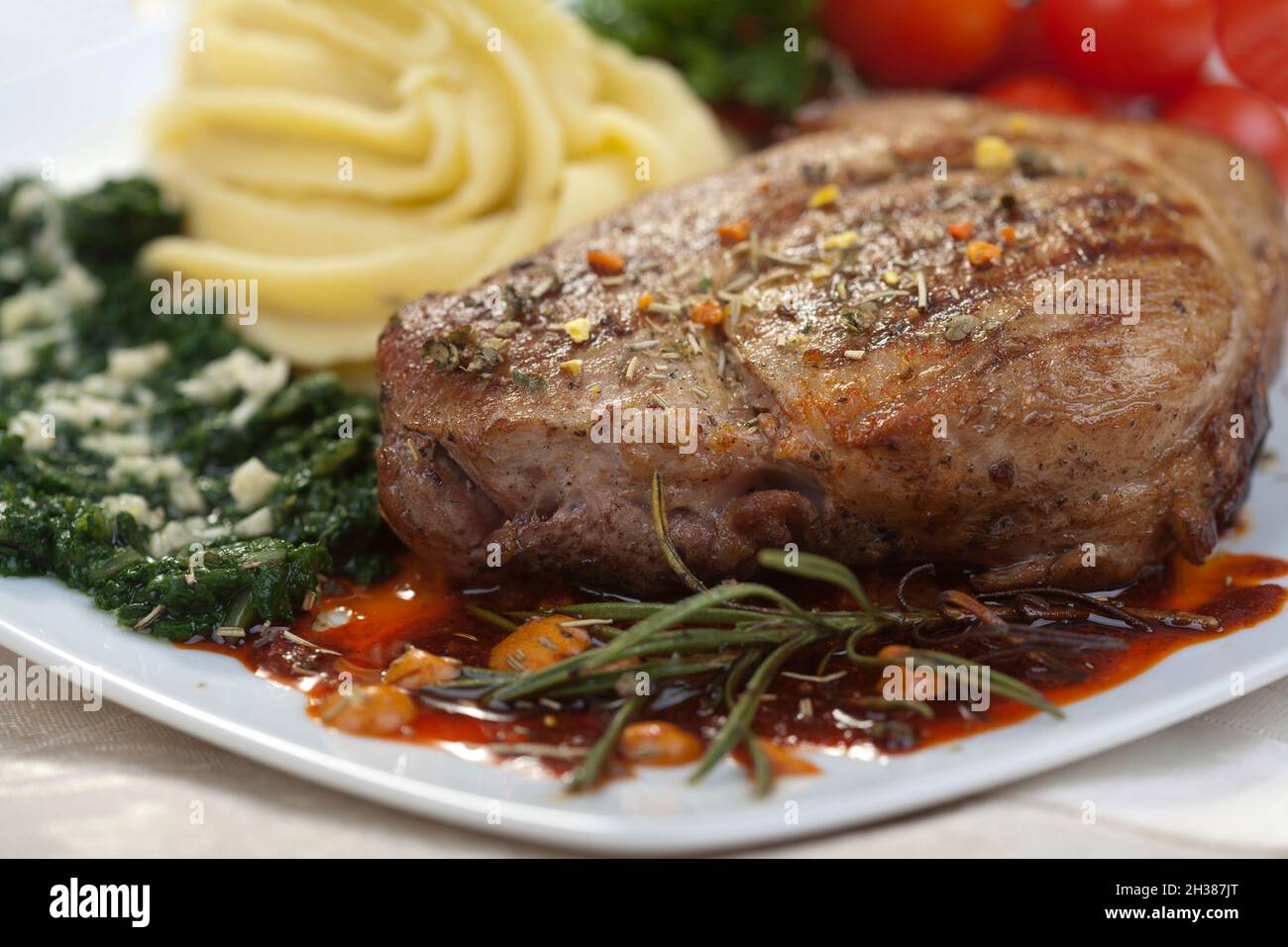 Deliziosa bistecca di manzo con spinaci e patate decorate con aglio Foto Stock