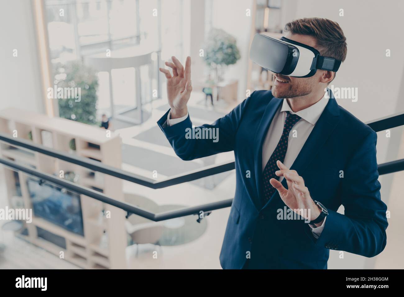 Giovane uomo d'affari che indossa occhiali per realtà virtuale che lavorano in ufficio Foto Stock