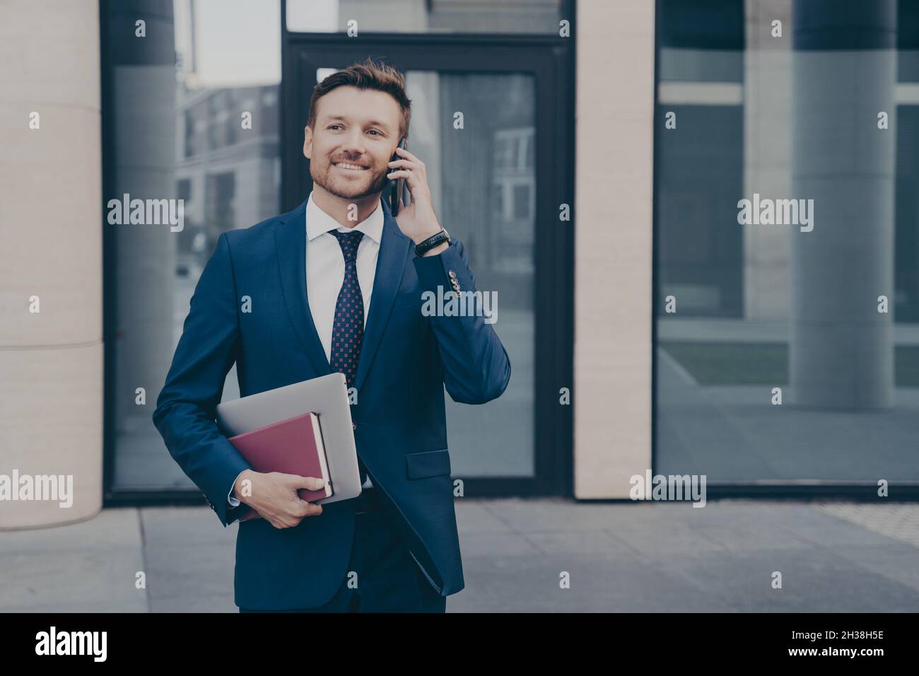 Il proprietario di affari riuscito e sicuro che parla al telefono con il suo impiegato all'aperto Foto Stock