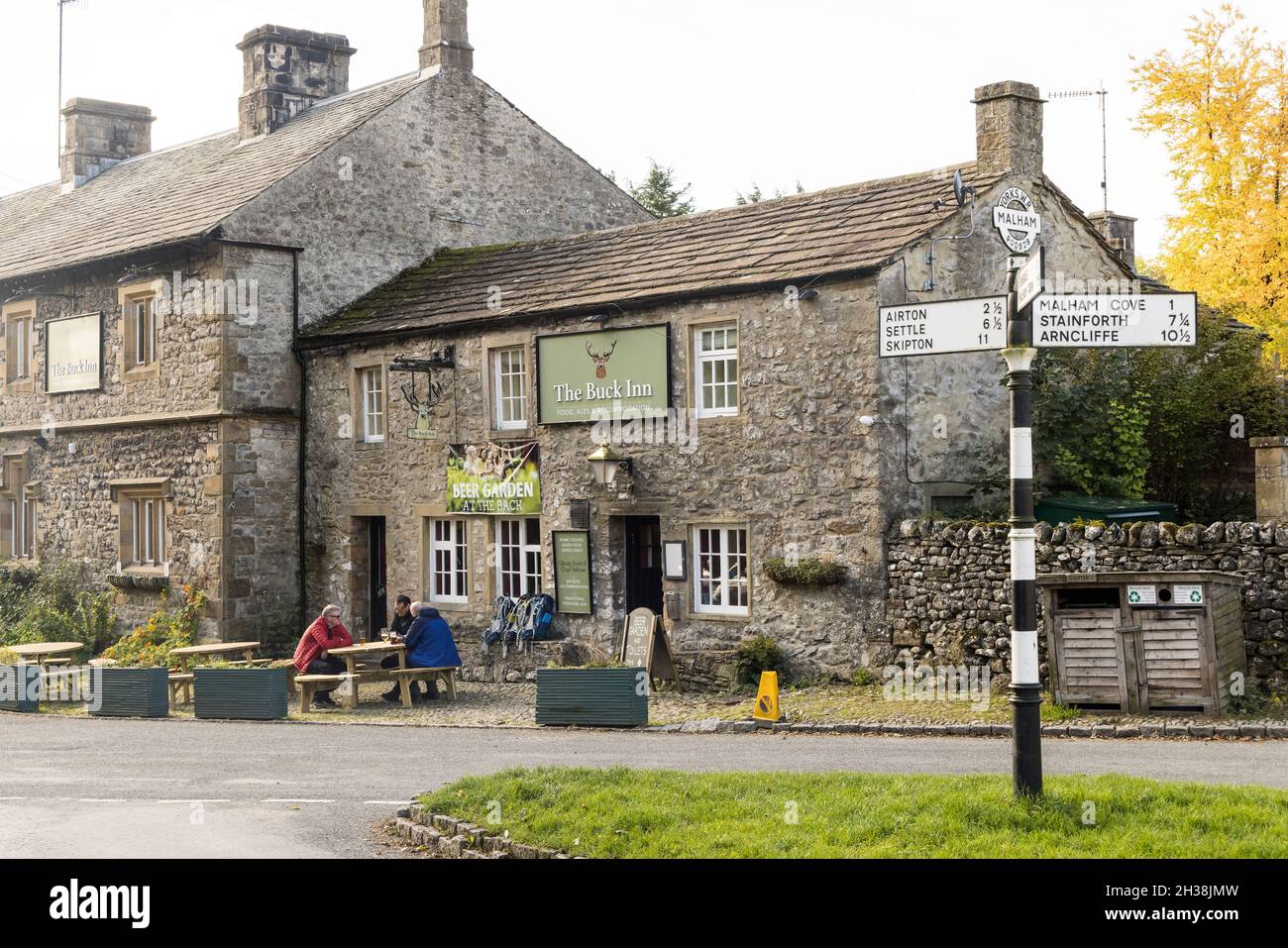 Persone che bevono fuori dal Buck Inn a Malham, con cartello tradizionale, Yorkshire, Regno Unito Foto Stock