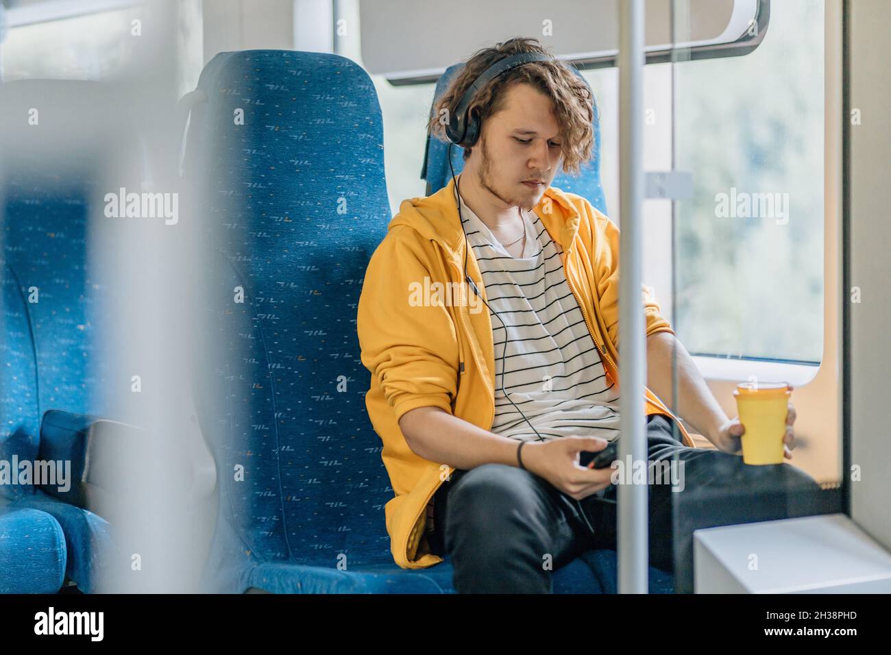 Giovane uomo, adolescente, viaggiando in treno bere caffè. Foto stile di vita. Foto Stock