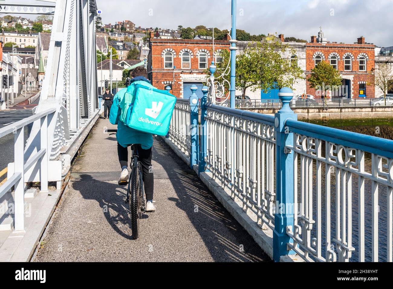 Deliveroo Rider attraversa il ponte Brian Boru a Cork City, Irlanda. Foto Stock