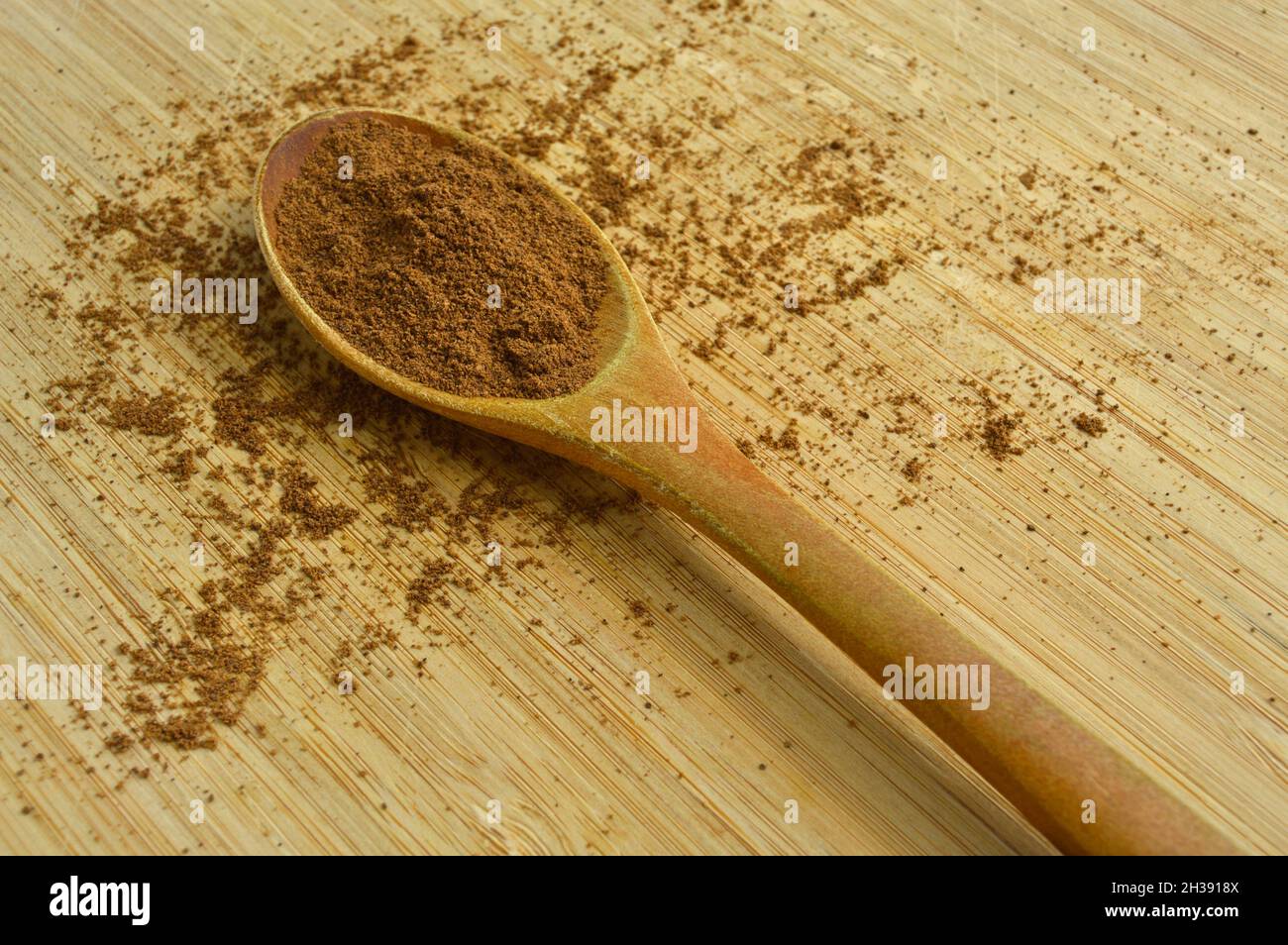 Spezie in polvere allspice in cucchiaio di legno, bambù su tagliere Foto Stock