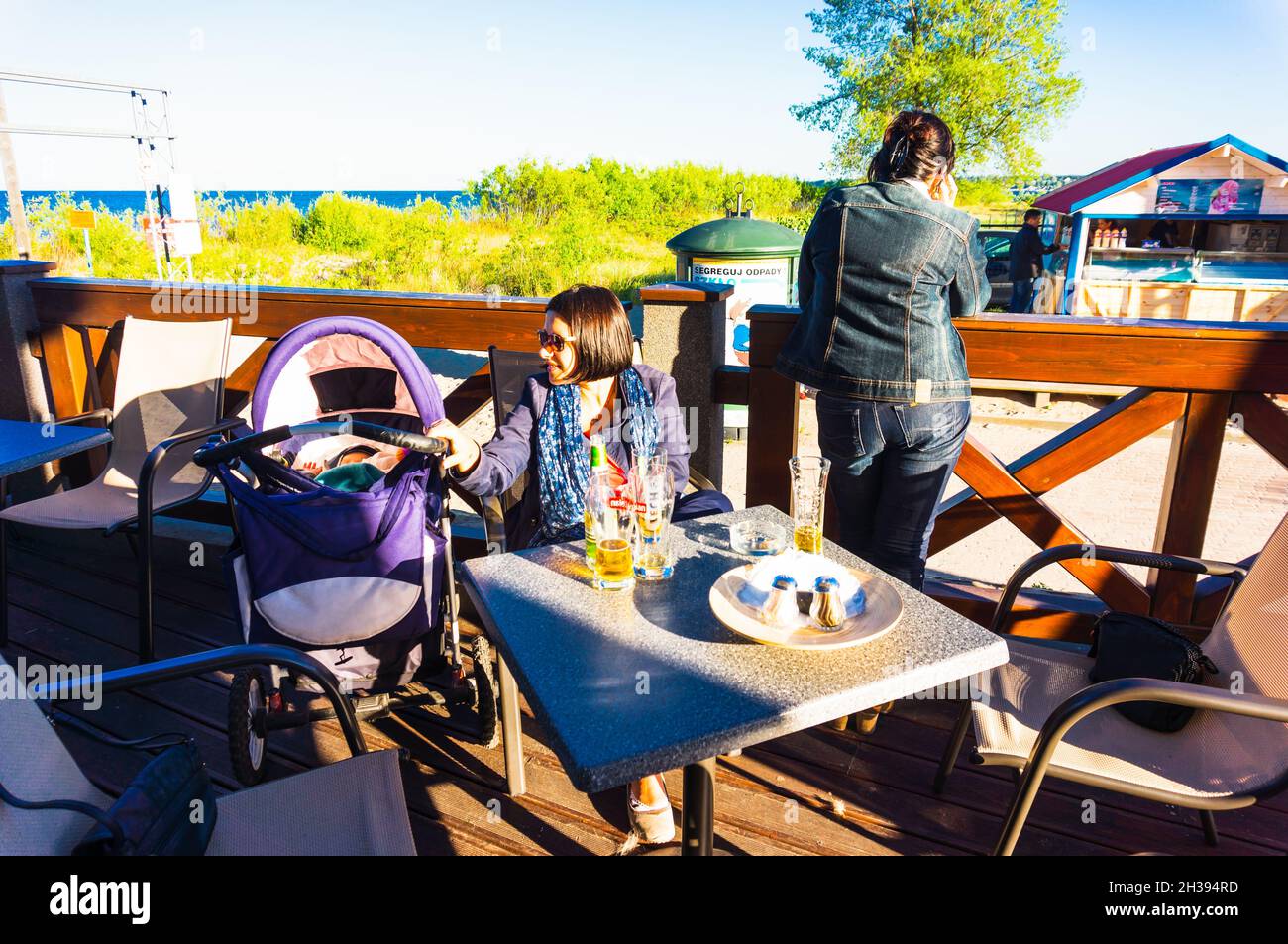 REWA, POLONIA - 15 giu 2014: Donne con un passeggino seduto ad un tavolo di un ristorante con bottiglie e bicchieri vuoti davanti Foto Stock