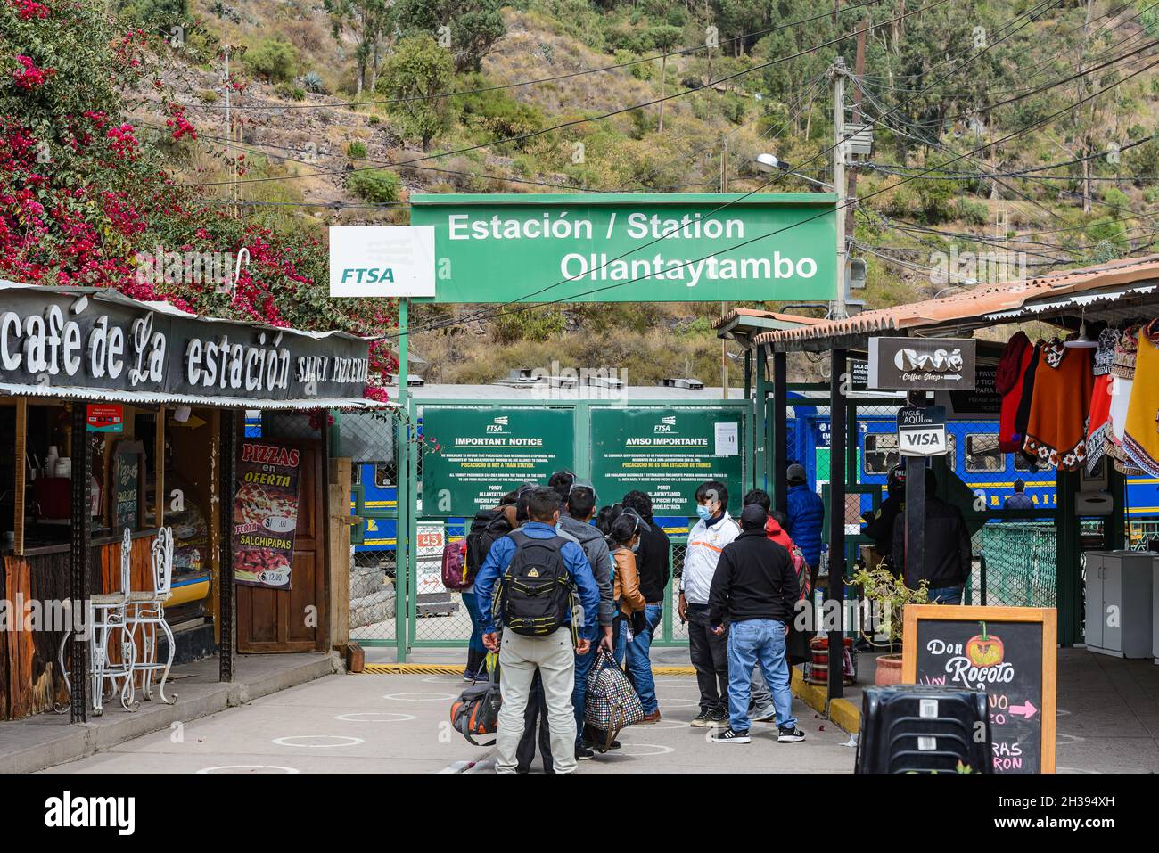 I viaggiatori si allineano al cancello per la stazione ferroviaria. Ollantaytambo, Cuzco, Perù. Foto Stock