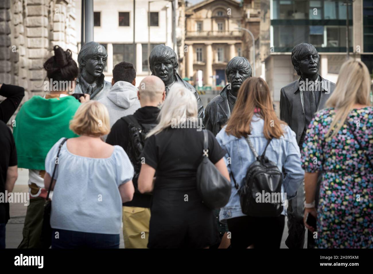I visitatori possono ammirare le statue di bronzo dei Beatles a Pier Head, Liverpool. Foto Stock