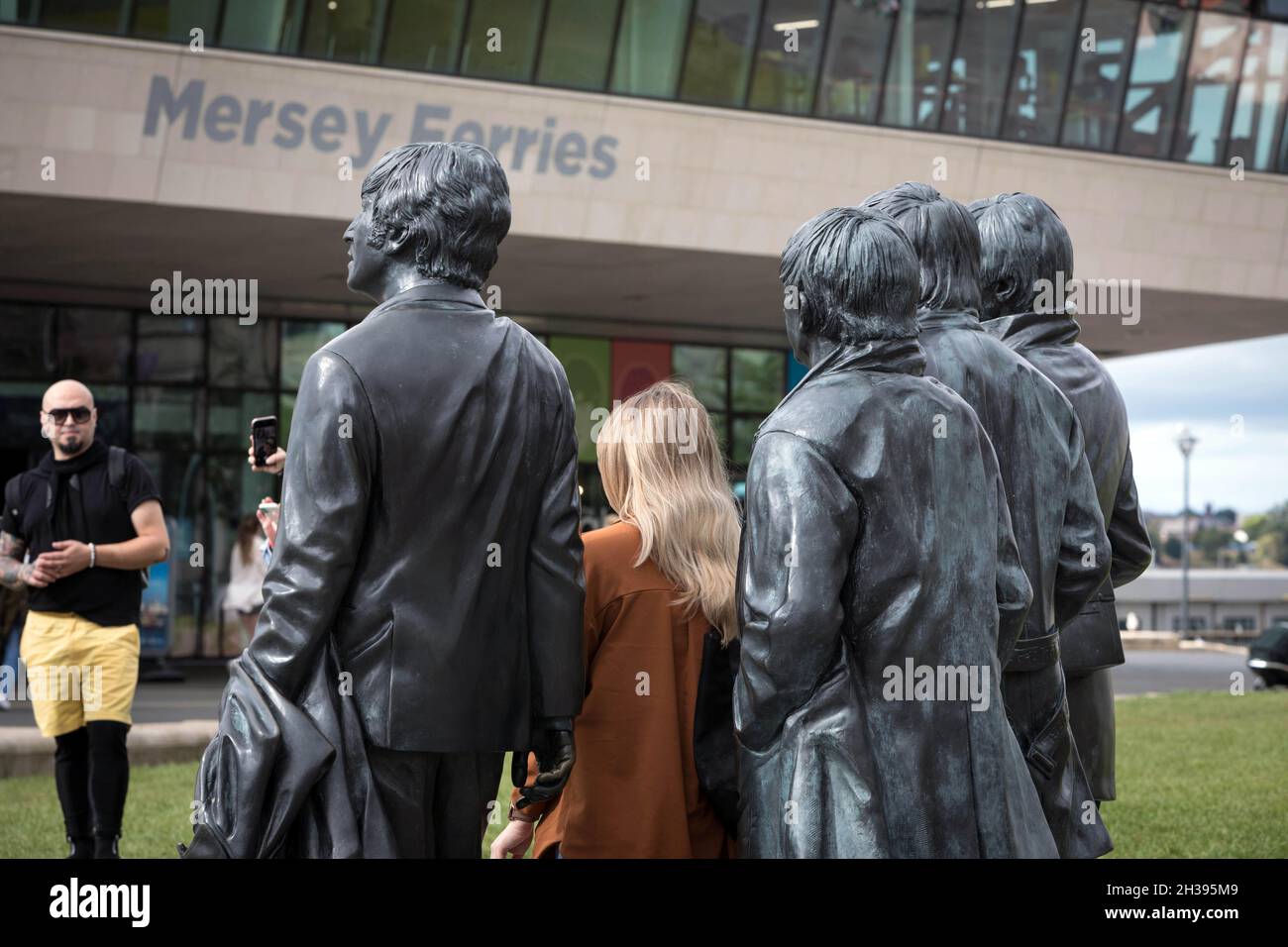 Un visitatore vede le statue di bronzo dei Beatles a Pier Head, Liverpool Foto Stock