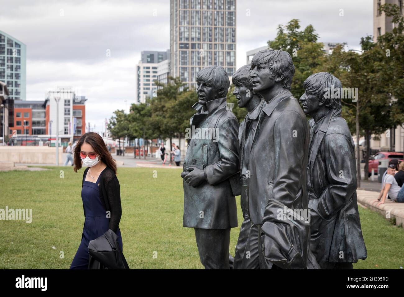 Un visitatore si pone con le statue di bronzo dei Beatles a Pier Head, Liverpool Foto Stock
