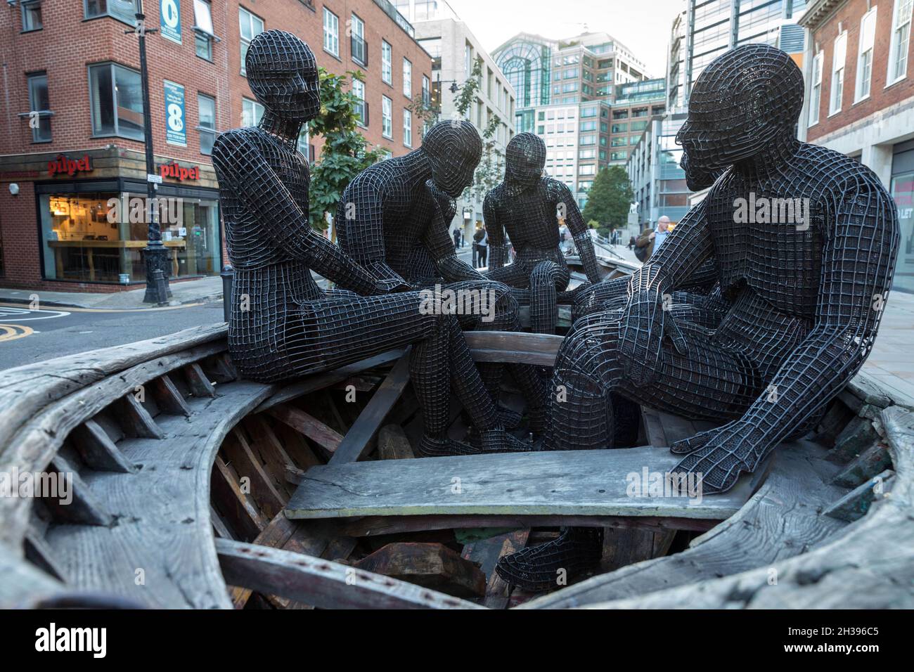 Sculture in barca su Brushfield Street, Spitalfields, Londra orientale. L'opera, di Kalliopi Lemos, presenta una barca utilizzata dai rifugiati turchi Foto Stock