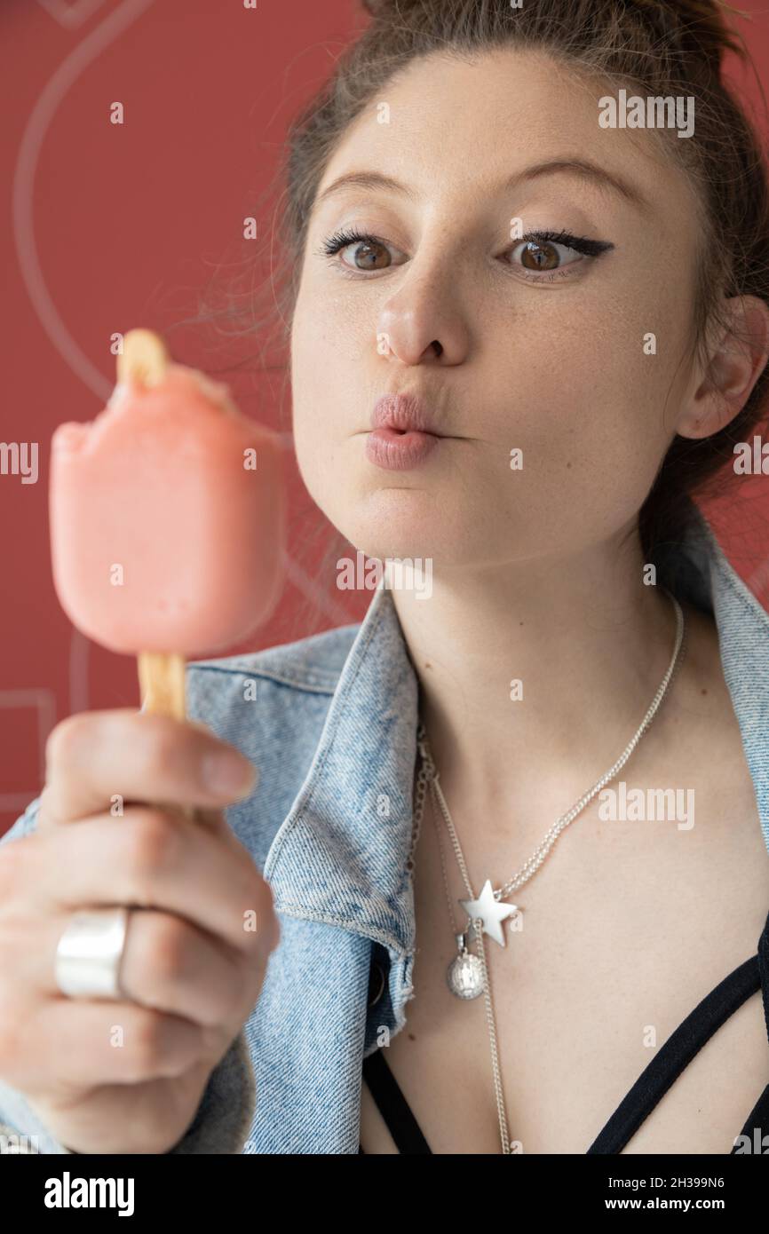 dettagli del volto di una bella giovane donna che si diverte mangiando gelato, stile di vita e gioia con il cibo, indossando collana e trucco Foto Stock