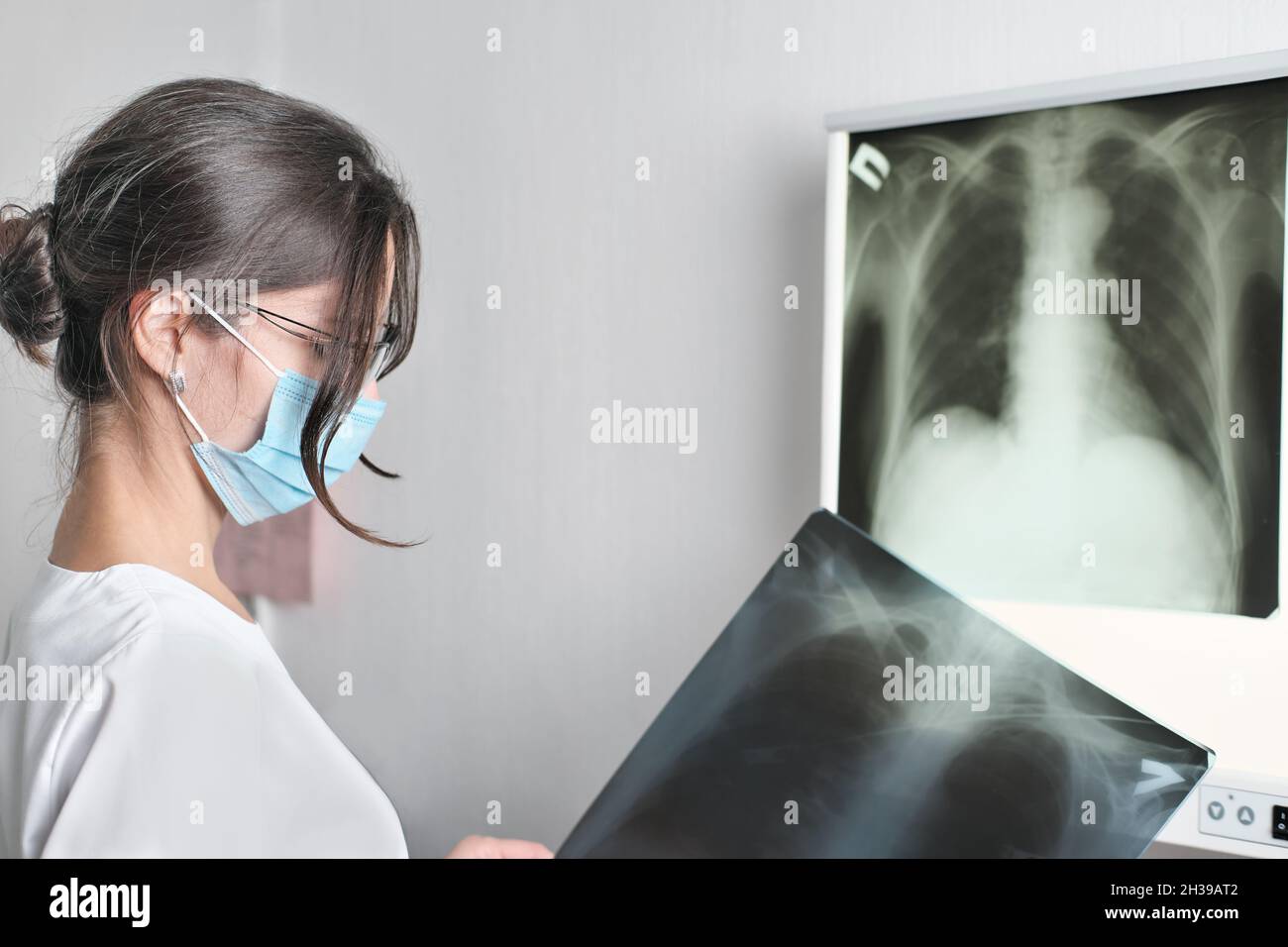 mixe race donna medico radiologo controllo film x-ray immagine dalla macchina. Analizzare un progresso della malattia. Concetto di assistenza sanitaria. Donna che indossa u. Medico Foto Stock