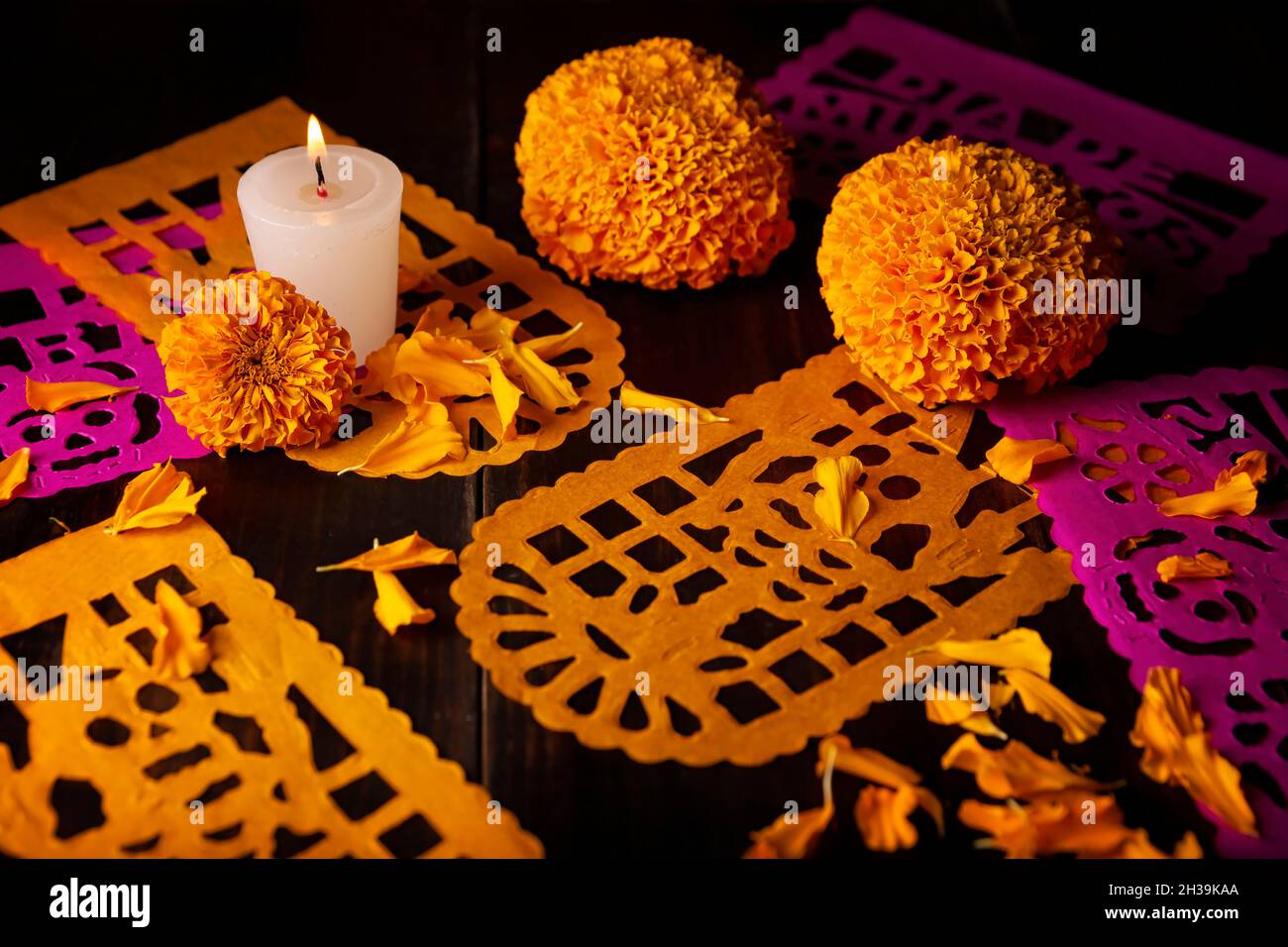 Candela con fiori d'arancio Cempasuchil o Marigold. (Tagetes erecta) e Papel Picado. Decorazione tradizionalmente utilizzata negli altari per la celebrazione di Foto Stock