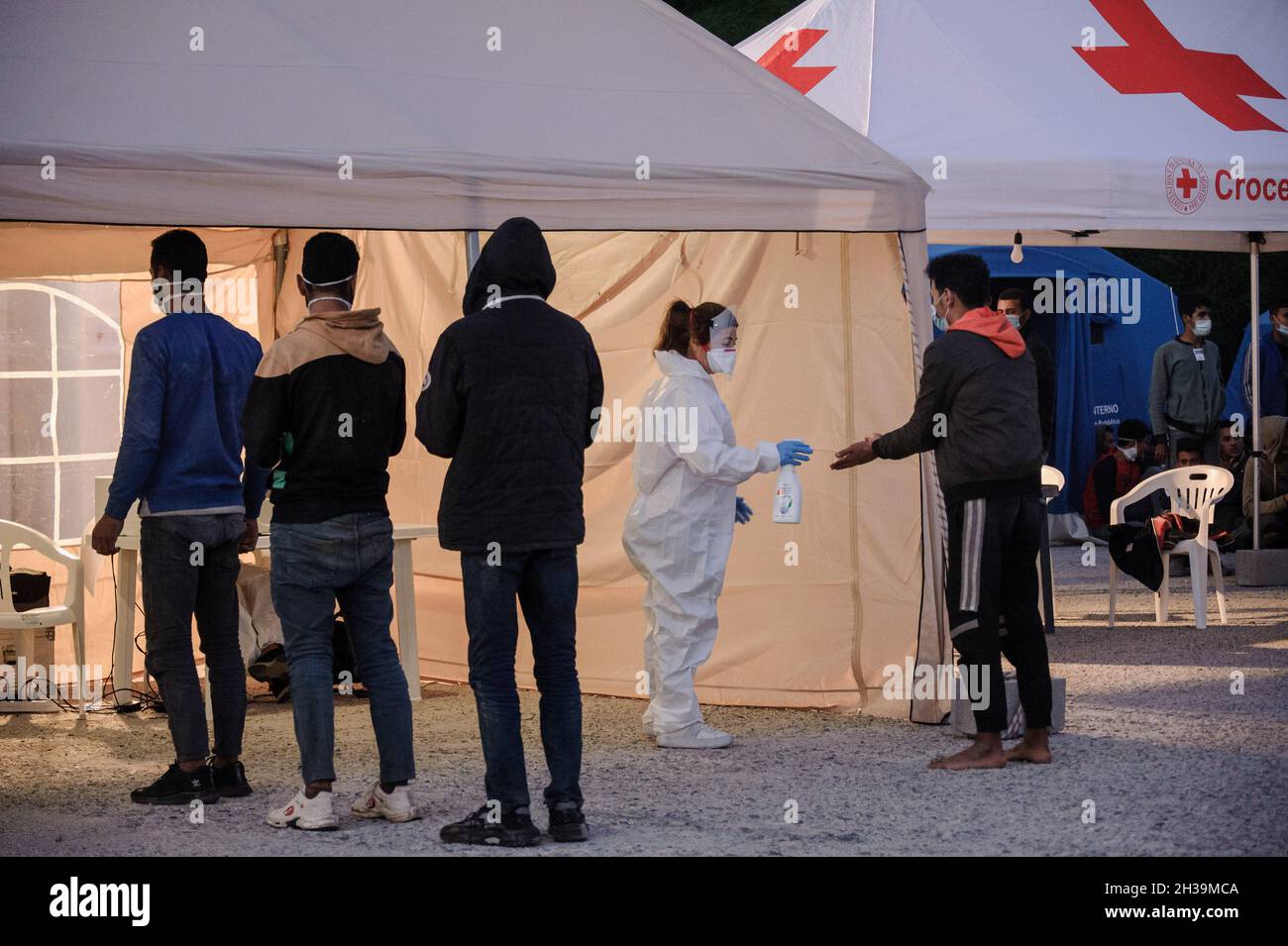 Roccella Jonica, Italia. 19 Ott 2021. Un membro della Croce Rossa ha visto disinfettare un migrante al porto di Roccella Jonica.quasi 299 migranti irregolari, principalmente egiziani e sudanesi, sono arrivati nel porto di Roccella Jonica (Calabria) dopo essere stati salvati dalla sezione navale della Guardia Finanza Italiana (Guardia di Finanza) a 30 miglia dalla costa. (Credit Image: © Valeria Ferraro/SOPA Images via ZUMA Press Wire) Foto Stock