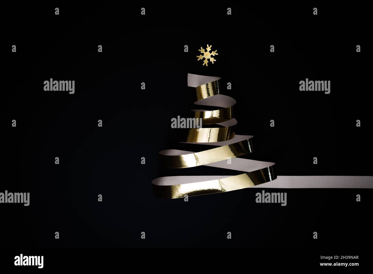 Festa di Natale o Capodanno concetto: Albero di Natale fatto di lucido nastro d'oro o streamer dorato su sfondo nero. Foto Stock