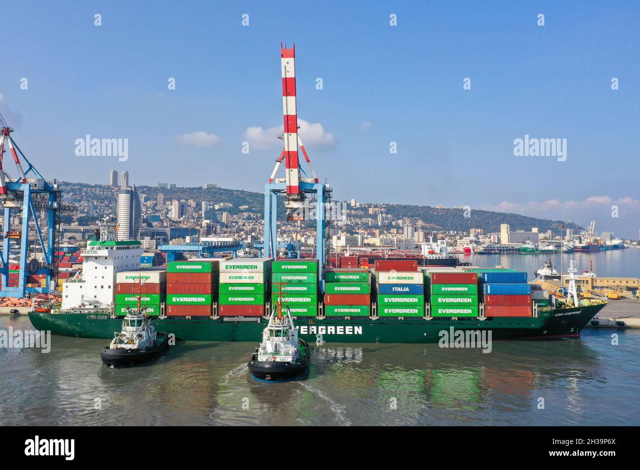 Rimorchiatori che dirigono una nave container Evergreen in un molo portuale. Foto Stock