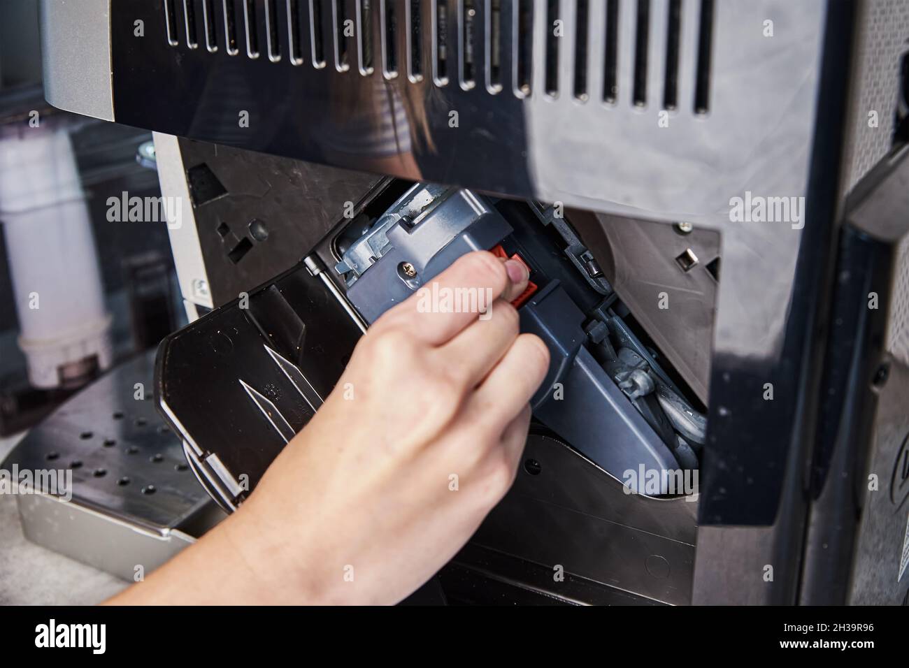 Pulizia automatica della macchina da caffè. Donna inserisce il meccanismo all'interno della macchina da caffè. Manutenzione di elettrodomestici Foto Stock