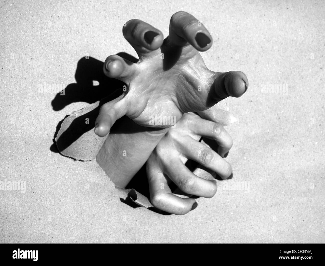 Le mani escono dal foro della carta da imballaggio. Foto Stock