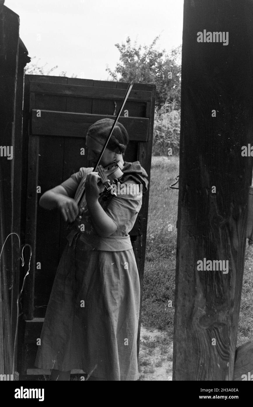 Eine Frau spielt Geige am Eingang einer Windmühle; Deutschland 1930er Jahre. Una donna che suona il violino mentre in piedi davanti alla porta di un mulino a vento; Germania 1930s. Foto Stock