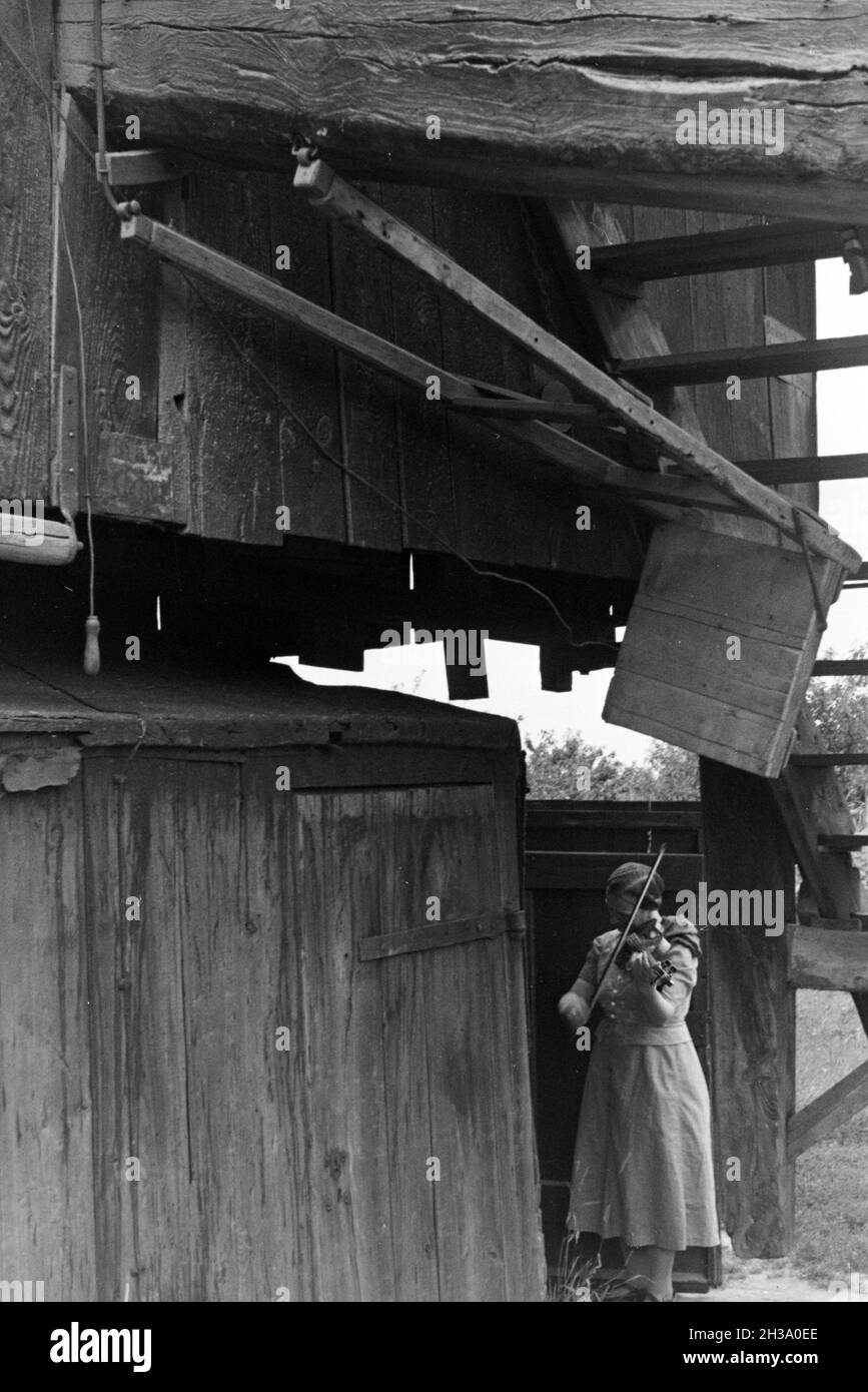 Eine Frau spielt Geige unter der Treppe einer Windmühle; Deutschland 1930er Jahre. Una donna che suona il violino mentre in piedi sotto le scale di un mulino a vento; Germania 1930s. Foto Stock