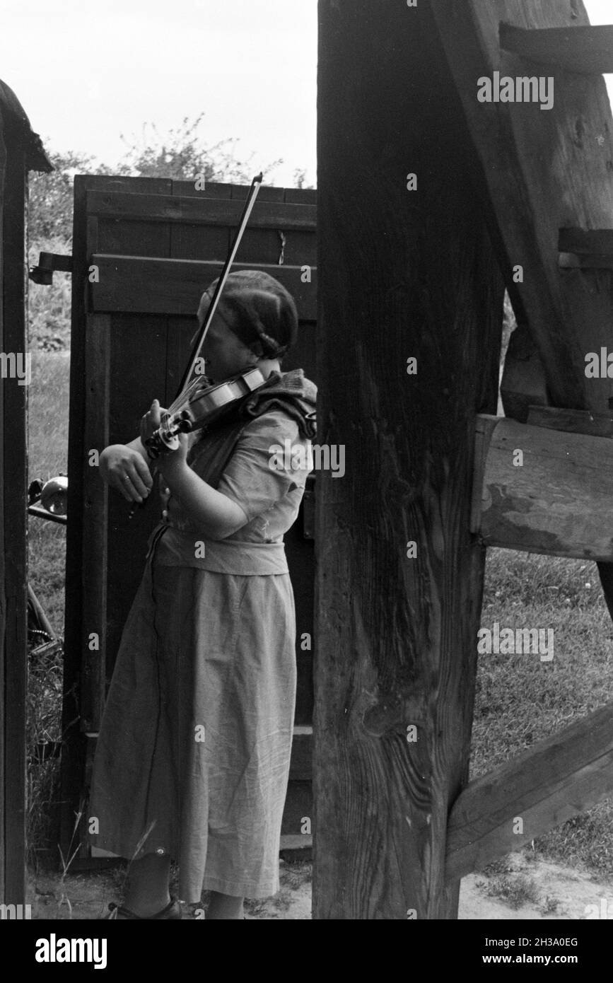Eine Frau spielt Geige am Eingang einer Windmühle; Deutschland 1930er Jahre. Una donna che suona il violino mentre in piedi davanti alla porta di un mulino a vento; Germania 1930s. Foto Stock