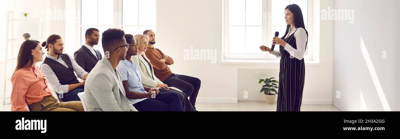 Banner con altoparlante femmina che tiene il microfono e parla per un pubblico diversificato Foto Stock