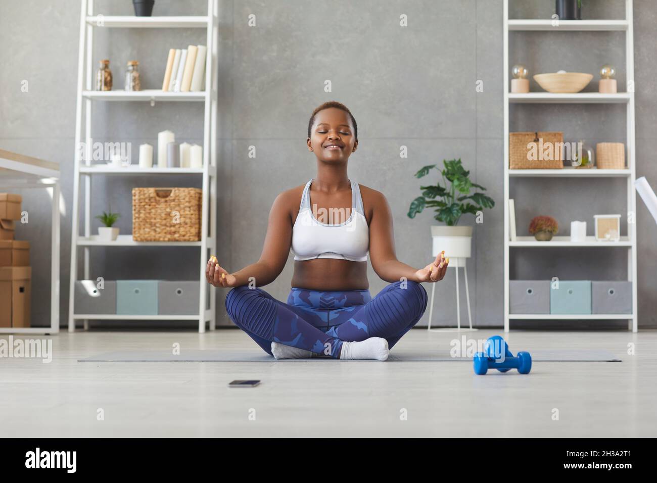 Calma biraciale donna pratica yoga meditate a casa Foto Stock