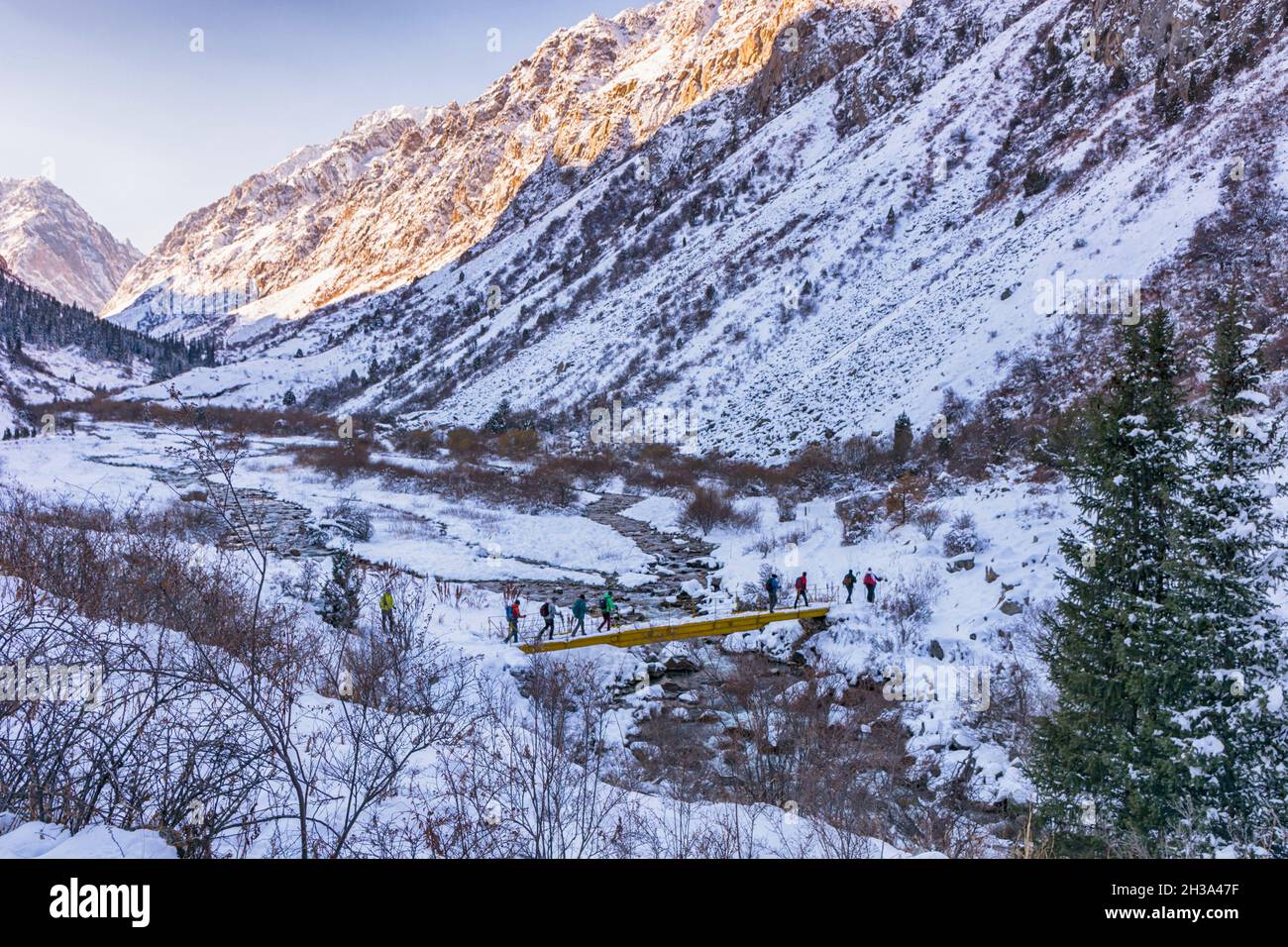 Idilliaco paesaggio invernale con le persone escursionistiche in montagna. Rocce, neve e pietre in vista valle di montagna. Foto Stock
