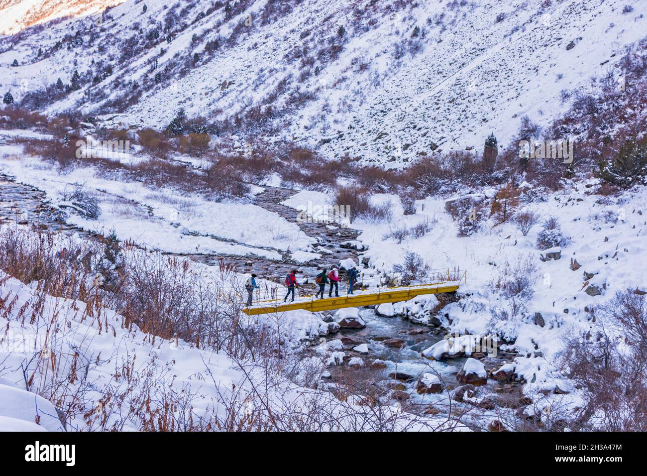 Idilliaco paesaggio invernale con le persone escursionistiche in montagna. Rocce, neve e pietre in vista valle di montagna. Foto Stock