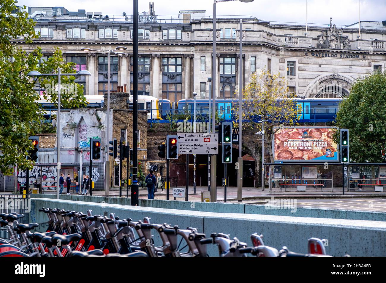Un treno Commuter Railway attraversa Un ponte stradale alla stazione di Waterloo con una fila di Paked ecologico Push Bikes a un Major Rod Junction Wi Foto Stock