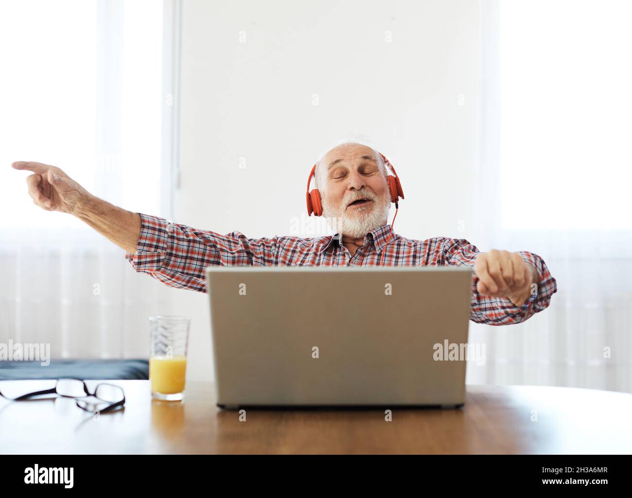 senior man laptop musica ascolto anziani cuffie auricolari tecnologia home Foto Stock