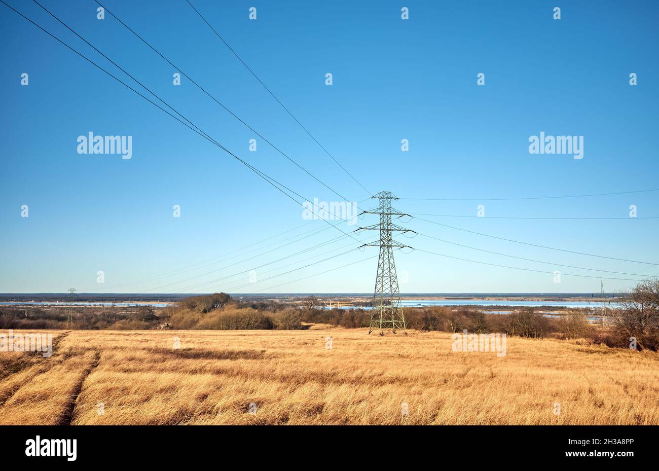 Paesaggio rurale con torre di trasmissione ad alta tensione su un campo. Foto Stock