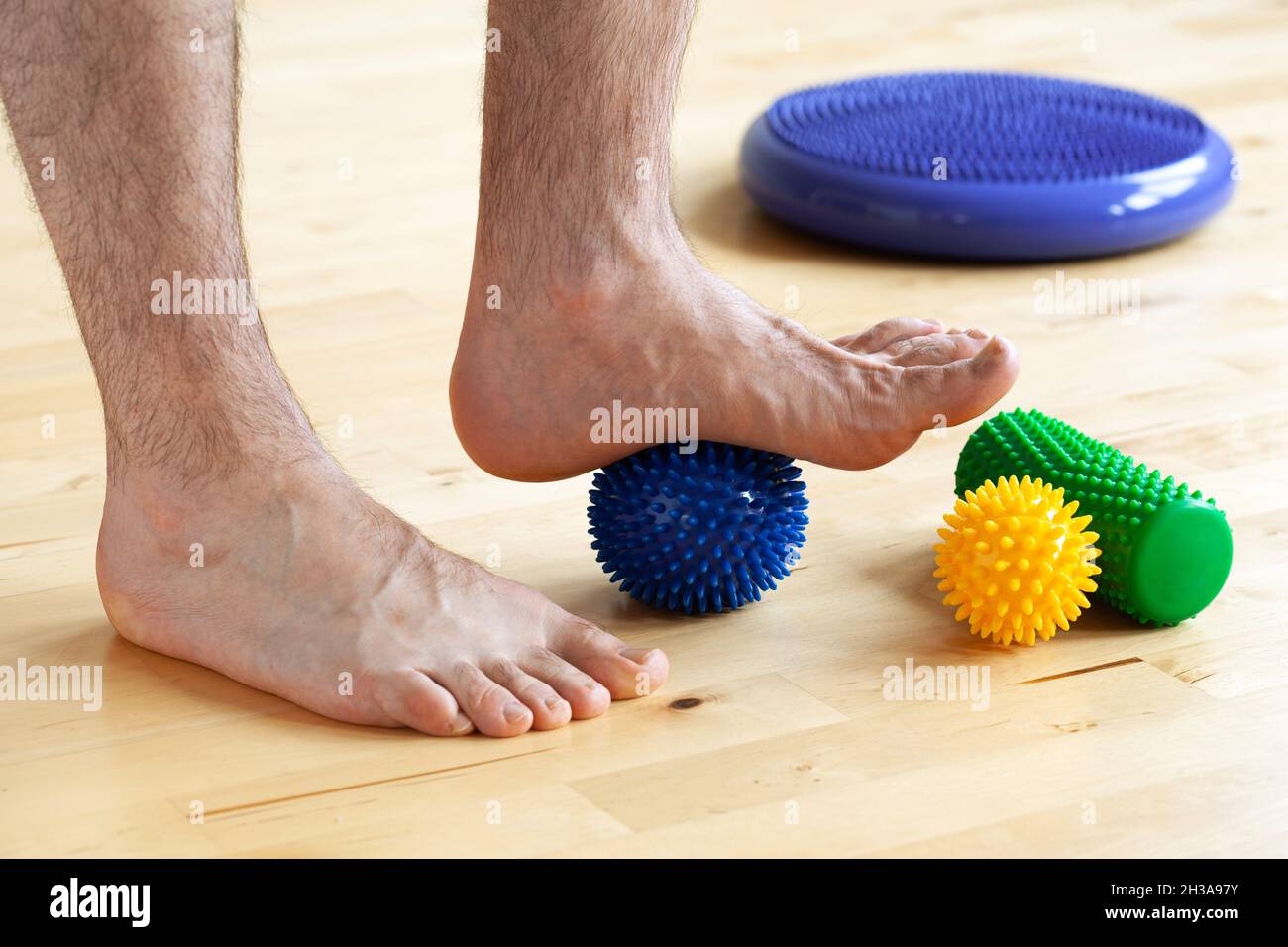 uomo che fa la ginnastica di correzione del piede piatto usando la sfera di massaggio nel paese Foto Stock
