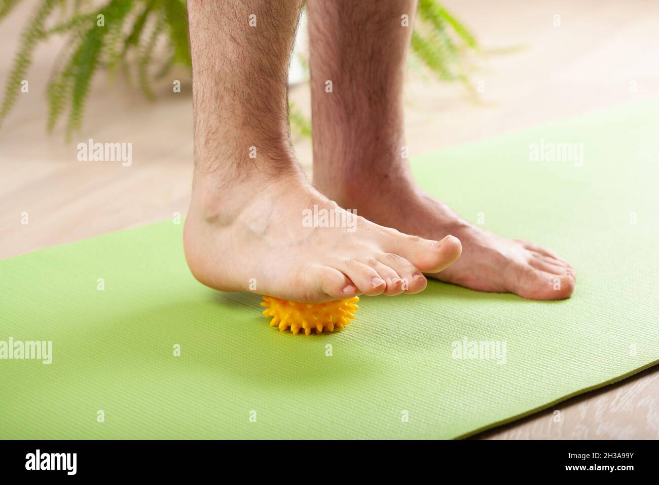 uomo che fa la ginnastica di correzione del piede piatto usando la sfera di massaggio nel paese Foto Stock
