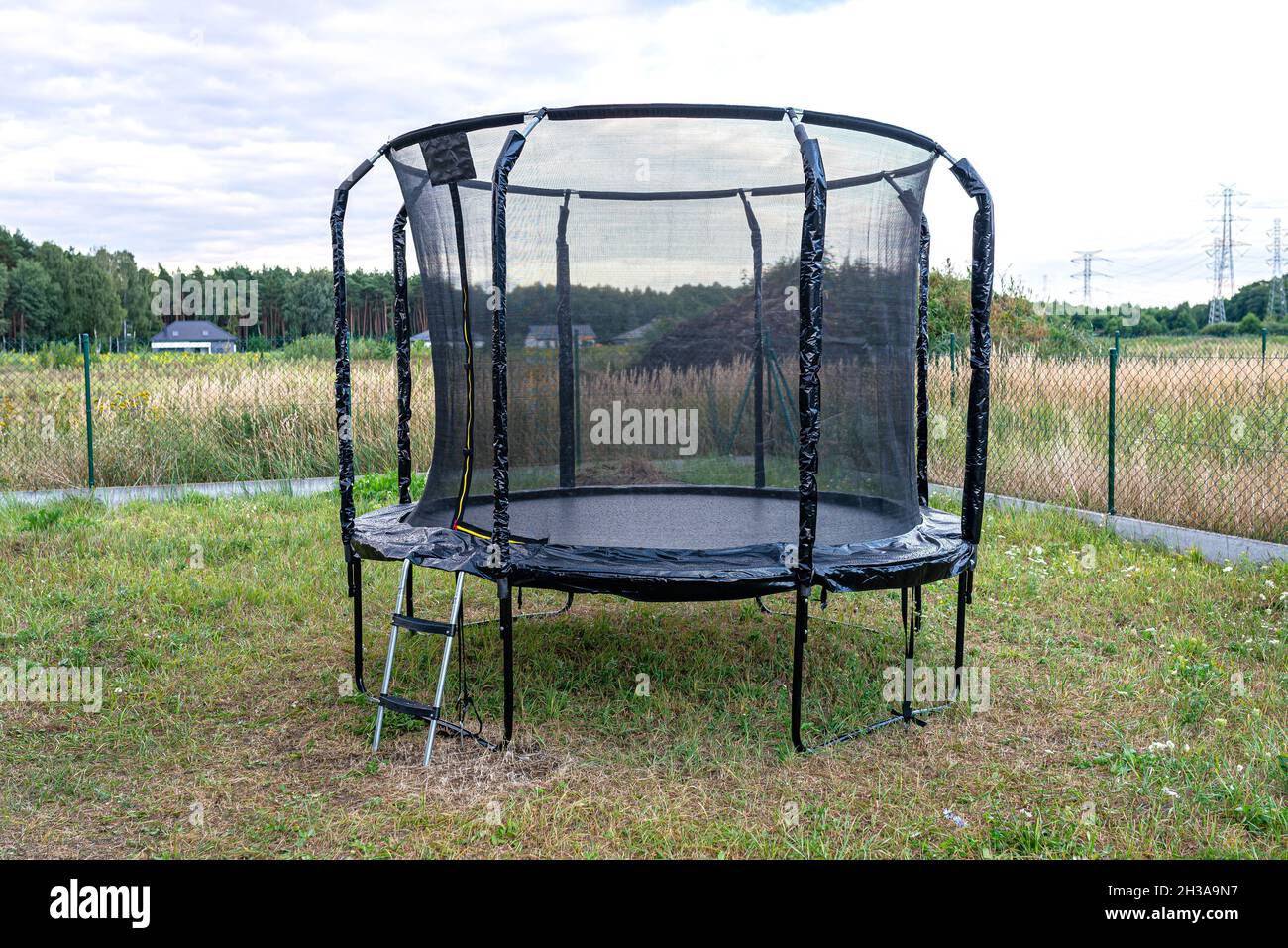Grande trampolino da salto per bambini con rete protettiva e cerniera chiusa, in piedi in giardino. Foto Stock