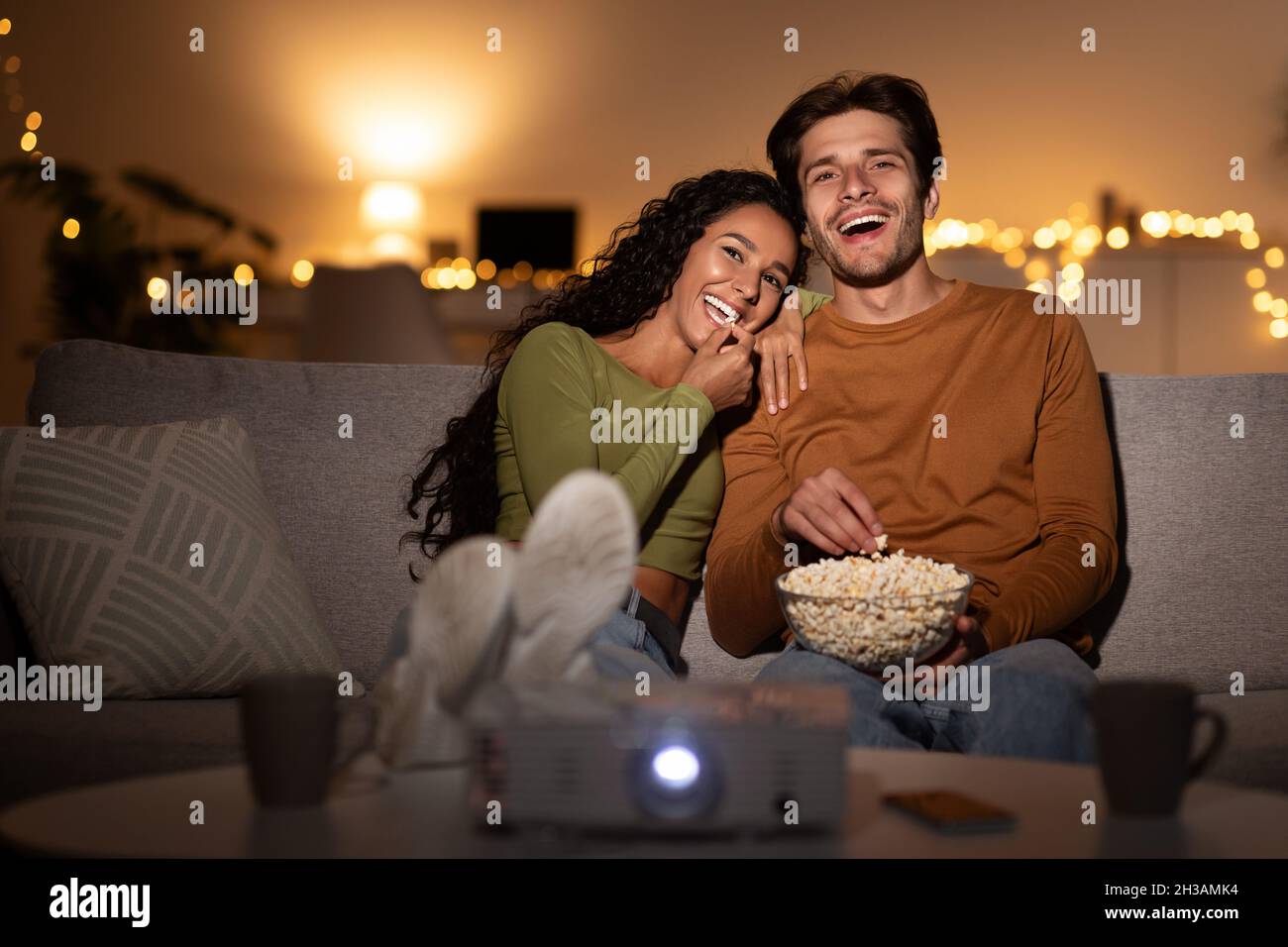 Sposi Laughing guardare Comedy Film mangiare Popcorn seduta al coperto Foto Stock