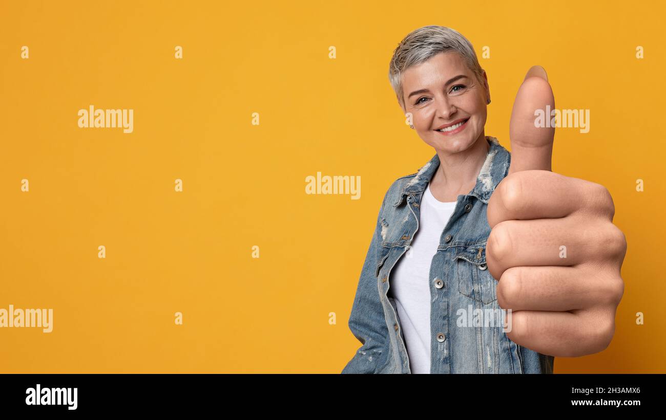 Sorridendo la signora matura gesturando il pollice in su alla macchina fotografica, spazio di copia Foto Stock
