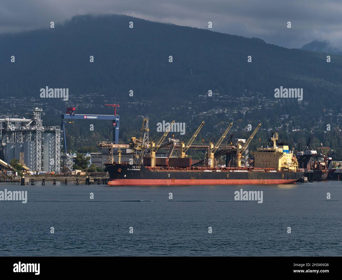 Portarinfuse DL Lavender ormeggio al porto di Vancouver Nord per il carico di fronte all'area industriale con colline coperte di nuvole sullo sfondo. Foto Stock