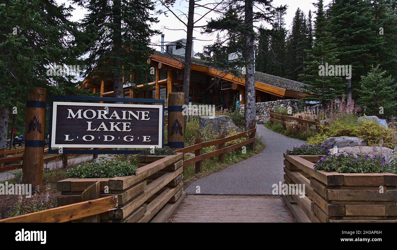 Vista frontale dell'entrata del famoso Moraine Lake Lodge nel Parco Nazionale di Banff nelle Montagne Rocciose Canadesi con cartello in legno circondato da foresta. Foto Stock