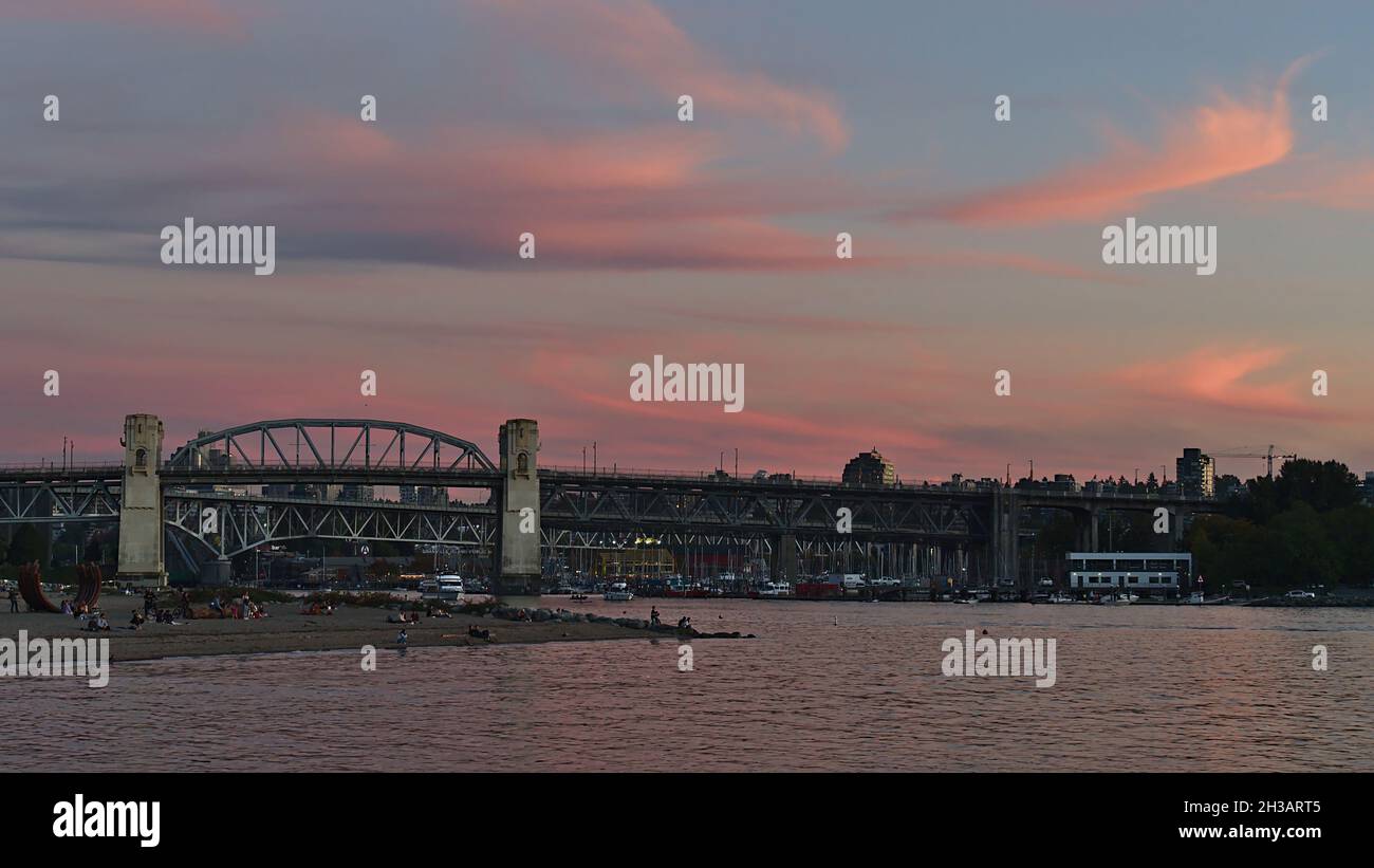 Vista mozzafiato delle persone che si godono la serata a Sunset Beach, nel centro di Vancouver con Burrard Street Bridge e il cielo rosa. Foto Stock