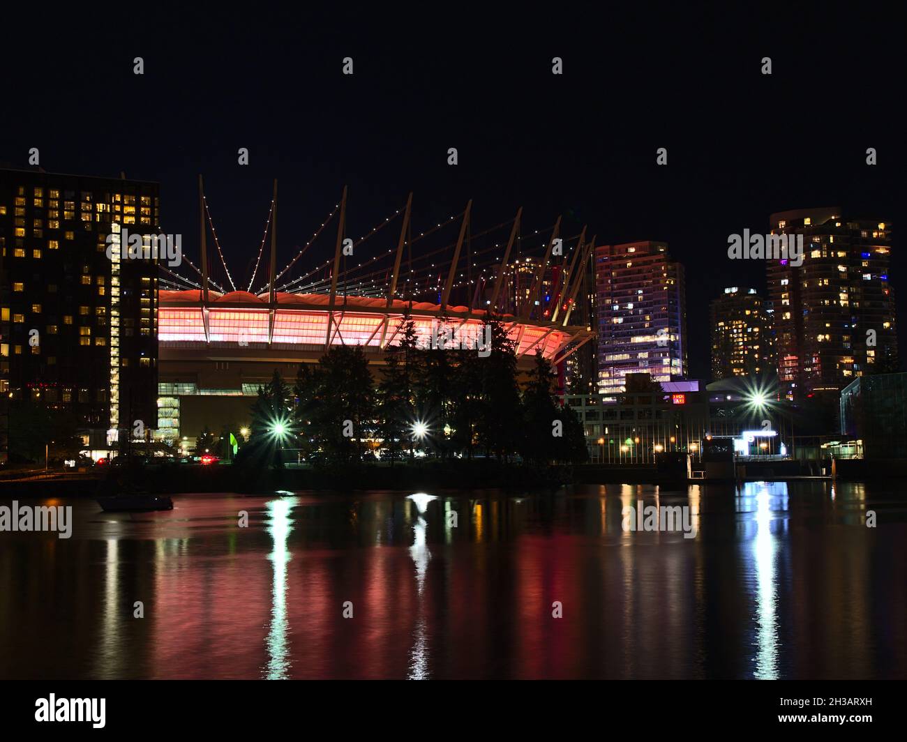 Splendida vista notturna della baia di False Creek, nel centro di Vancouver con il BC Place Stadium illuminato che si riflette nelle acque calme e negli edifici residenziali. Foto Stock